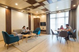 德拉敦The Homely Homestay Near Pacific Mall Dehradun的一群人坐在客厅的桌子上