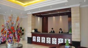 a hotel lobby with two people in a mirror at GreenTree Inn Shanghai Songjiang Xinqiao Jiuxin Road Express Hotel in Chunshen