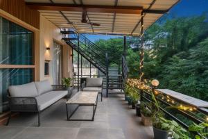 德拉敦The Homely Homestay Near Pacific Mall Dehradun的带椅子的露台和带灯的楼梯