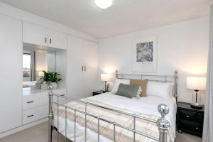 une chambre blanche avec un lit et un miroir dans l'établissement Del Boca Vista Tuncurry, à Tuncurry