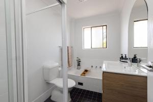 une salle de bain blanche avec toilettes et lavabo dans l'établissement Del Boca Vista Tuncurry, à Tuncurry