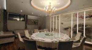 a dining room with a table and chairs and a chandelier at Metropark Hotel in Huludao