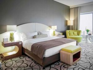 una camera con un grande letto e una sedia verde di Sofitel Dubai Downtown a Dubai