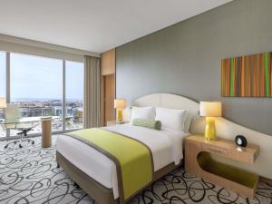una camera da letto con un letto grande e una grande finestra di Sofitel Dubai Downtown a Dubai