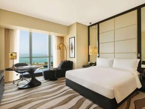 a hotel room with a bed and a desk and a table at Sofitel Abu Dhabi Corniche in Abu Dhabi