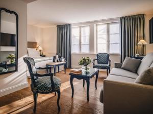 a living room with a bed and a couch at Cour du Corbeau Hotel Strasbourg - MGallery Collection in Strasbourg