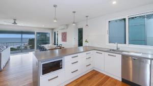 a kitchen with white cabinets and a view of the ocean at Point View - 'amazing Views =& Location=' in Avoca Beach