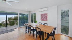 a dining room with a wooden table and chairs at Point View - 'amazing Views =& Location=' in Avoca Beach