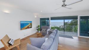 a living room with a couch and a ceiling fan at Point View - 'amazing Views =& Location=' in Avoca Beach