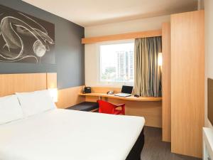 a room with a bed and a desk with a laptop at ibis Mogi das Cruzes Shopping in Mogi das Cruzes +66 photos