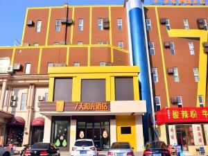a yellow building with cars parked in front of it at 7 Days Inn Tai'an Dongpingxi Hualian in Dongping