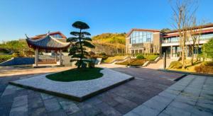 a tree in a courtyard in front of a building at Tiantai He hotel in Tiantai