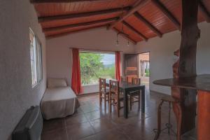 sala de estar con mesa, cama y ventana en Cabañas La Ernestina, en Villa Carlos Paz