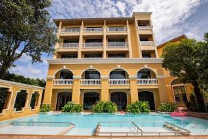 クラビタウンにあるThe Pineapple Hotelの大きな黄色の建物で、目の前にスイミングプールがあります。