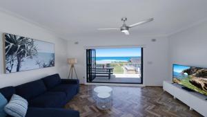 a living room with a blue couch and a tv at Elanora 3 - Beachfront Unit With Views! in Avoca Beach