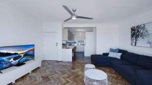 a living room with a blue couch and a tv at Elanora 3 - Beachfront Unit With Views! in Avoca Beach