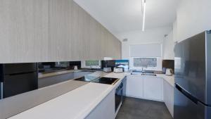a kitchen with white cabinets and a black refrigerator at Elanora 3 - Beachfront Unit With Views! in Avoca Beach