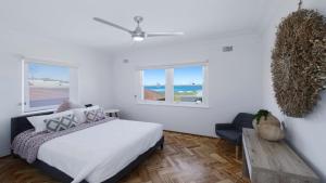 a bedroom with a bed and a table and two windows at Elanora 3 - Beachfront Unit With Views! in Avoca Beach +7 photos
