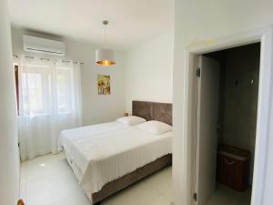 ein weißes Schlafzimmer mit einem Bett und einem Fenster in der Unterkunft Renovierte Ferienwohnung in Ravni mit Schöner Terrasse und Meerblick in Ravni