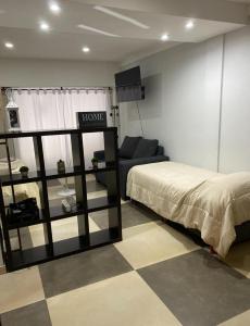 ein Schlafzimmer mit einem Bett und einer Couch in einem Zimmer in der Unterkunft Apart Duclout Monte Grande a 15 minutos del Aeropuerto in Monte Grande