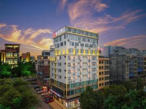 a tall white building in a city at dusk at Borrman Hotel Guigang Pingnan Donghu in Pingnan