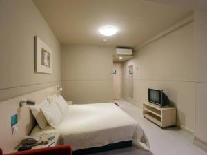 a hotel room with a bed and a television at Jinjiang Inn Hefei Sanxiaokou Lujiang Road in Hefei