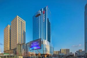 a tall building with a sign in a city at E-Cheng Hotel Shenyang North Railway Station in Shenyang