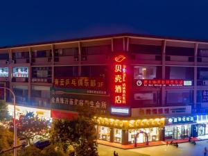 a building with a red sign on the side of it at Shell Hotel Suzhou Zhangjiagang Jingang Town Central Plaza in Xiwujieqiao
