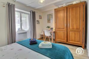 a bedroom with a bed with a blue blanket and a table at Le tigite b&b in Saint-Jean-la-Poterie