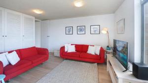 a living room with a red couch and a tv at Seaview 7 - Prime Position Beachside Holiday in Avoca Beach