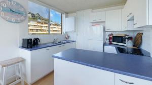 a kitchen with white cabinets and a blue counter top at Seaview 7 - Prime Position Beachside Holiday in Avoca Beach