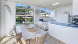 a kitchen with white cabinets and a table and chairs at Seaview 7 - Prime Position Beachside Holiday in Avoca Beach
