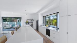 a white kitchen with a long table and a dining room at Omaroo House - Views Over Copa Beach in Copacabana