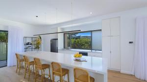 a kitchen with a large white island with chairs at Omaroo House - Views Over Copa Beach in Copacabana