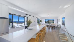 a dining room with a long white table and chairs at Omaroo House - Views Over Copa Beach in Copacabana