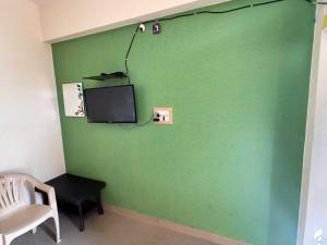 a green wall with a tv and a chair at Hotel O Hill Top Hotel in Vānivilāsa Puram
