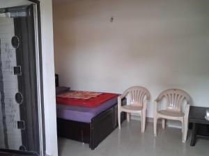 a bedroom with a bed and two chairs at Hotel O Hill Top Hotel in Vānivilāsa Puram