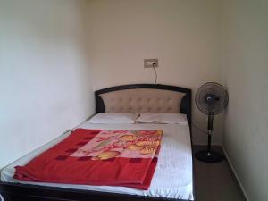 a bed with a red blanket on it with a fan at Hotel O Hill Top Hotel in Vānivilāsa Puram