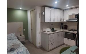 Una cocina con gabinetes blancos y una cama en una habitación. en ApartaSuite 2 a 3 personas cerca club campestre, en Medellín 29 fotos más