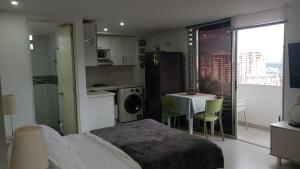 Un dormitorio con una cama y una mesa y una cocina. en ApartaSuite 2 a 3 personas cerca club campestre, en Medellín