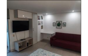 Una sala de estar con un sofá y un televisor de pantalla plana. en ApartaSuite 2 a 3 personas cerca club campestre, en Medellín