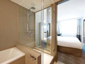 ウッチにあるNovotel Lodz Centrumのバスルーム(シャワー、バスタブ付)、ベッド1台が備わります。