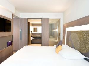 ウッチにあるNovotel Lodz Centrumのベッドとバスルームがあるホテルの部屋