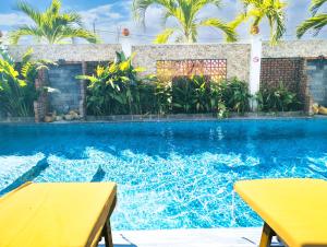 a swimming pool with two tables and palm trees at EasyLife Villa Hội An in Tân Thành (1)