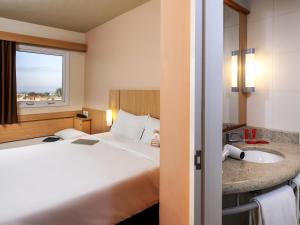 um quarto de hotel com uma cama e uma pia em ibis Ourinhos em Ourinhos mais 116 fotografias