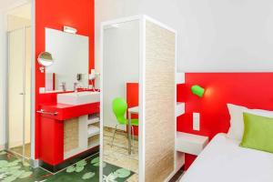 a bedroom with a red wall with a sink and a mirror at ibis Styles Karlsruhe Ettlingen in Ettlingen +74 photos