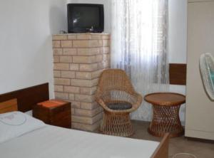a room with a fireplace with a chair and a tv at Apartments Miki Rogoznica in Podglavica
