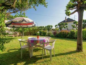 einen Tisch und Stühle unter einem Regenschirm im Hof in der Unterkunft Cozy Garden Retreat Malemort in Malemort-sur-Corrèze