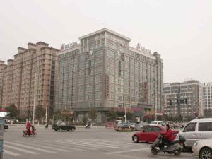 a large building with cars and people riding motorcycles in a parking lot at Jinjiang Inn Yancheng Railway Station in Yancheng