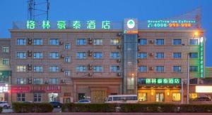 een gebouw met neonborden aan de voorzijde bij Green Tree Inn Urumqi San'gong Metro Station Exit in Ürümqi